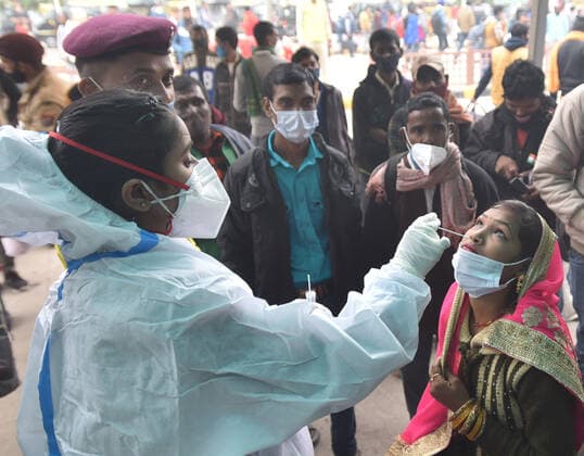 NEW DELHI, INDIA - DECEMBER 2: A health worker collects a swab sample of a passenger for Covid-19 test during a special testing camp organised after Omicron Covid Variant identified at Anand Vihar Railway Station, on December 2, 2021 in New Delhi, India. (Photo by Sonu Mehta Hindustan Times) Daily Life Amid Coronavirus Pandemic In India