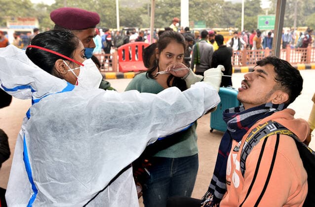 NEW DELHI, INDIA - DECEMBER 2: A health worker collects a swab sample of a passenger for Covid-19 test during a special testing camp organised after Omicron Covid Variant identified at Anand Vihar Railway Station, on December 2, 2021 in New Delhi, India. (Photo by Sonu Mehta Hindustan Times) Daily Life Amid Coronavirus Pandemic In India