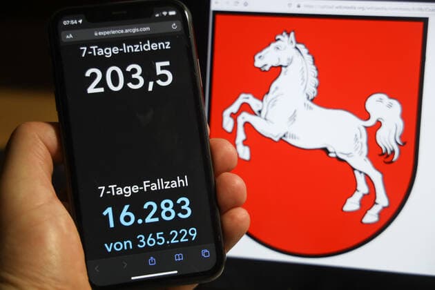 Coronavirus in Germany Covid 19 Dashboard of the Robert Koch Institute DEU, Germany, Lower Saxony 05 12 2021 The 7-day incidence for the state Cases last 7 days 100 000 PE is displayed on an iPhone, with the state coat of arms in the background.