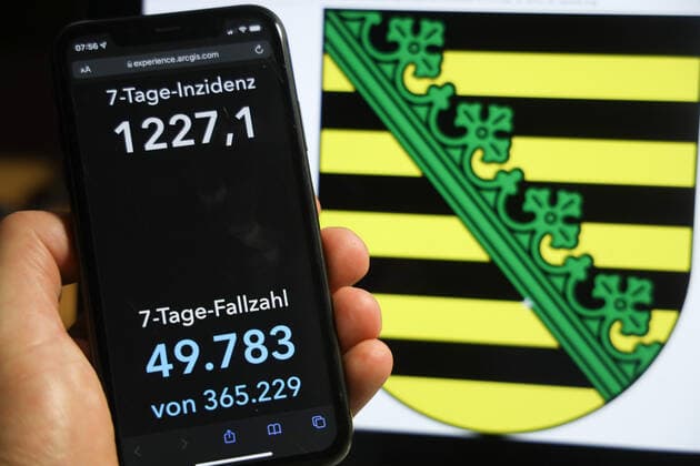 Coronavirus in Germany Covid 19 Dashboard of the Robert Koch Institute DEU, Germany, Saxony 05 12 2021 The 7-day incidence for the state Cases last 7 days 100 000 PE is displayed on an iPhone, with the state coat of arms in the background.