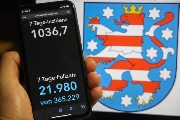 Coronavirus in Germany Covid 19 Dashboard of the Robert Koch Institute DEU, Germany, Thuringia 05 12 2021 The 7-day incidence for the state Cases last 7 days 100 000 p.e. is displayed on an iPhone, with the state coat of arms in the background.