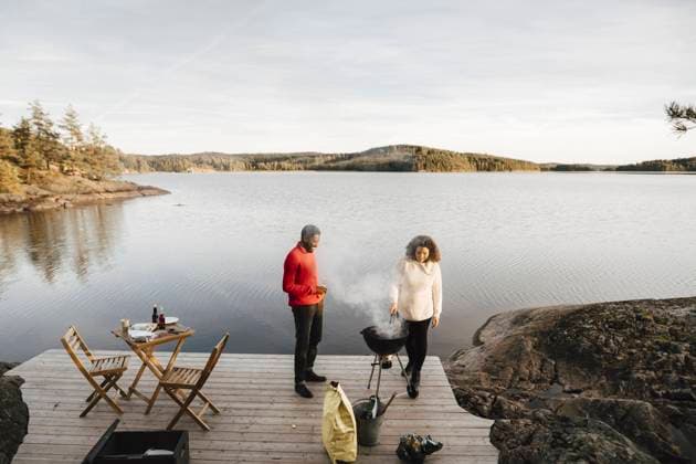 Full length of couple preparing food on barbecue grill against lake Sweden, Dalsland, model released Copyright: xMaskotx , MA90275