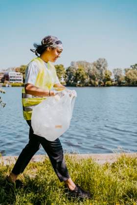 IMAGO Creative: Nächste Generation, Sozial- und klimabewusst Female environmentalist walking with plastic bag by lake Germany, Berlin, model released Copyright: xMaskotx , MA90305