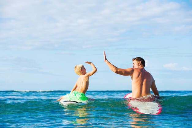 IMAGO Creative: Lokalhelden - Jugendsportbildung Happy Father And Young Son Going Surfing Together Copyright: DesignxPicsxVibe 12301641