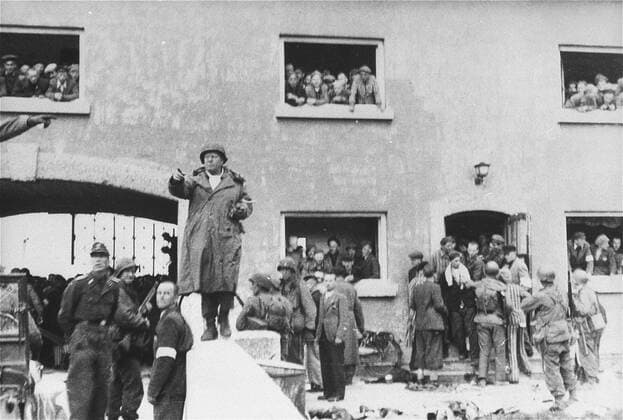 The surrender of the Dachau concentration camp to American forces of the Army™s 42nd Infantry Division, April 29, 1945 in Dachau, Germany. U.S. Army Brig. Gen. Henning Linden, assistant commanding general, 42nd Rainbow Infantry Division, gives directions to his troops from the bridge to the Jourhaus gate entrance to the Dachau concentration camp. The civilian with the white armband is Dr. Victor Maurer of the ICRC (International Red Cross). The German officer to the left is SS Lt. Heinrich Wickert (Wicker), the German officer who surrendered the camp. American Soldiers of the U.S. 7th Army, including the 42nd Infantry and 45th Infantry and 20th Armored Divisions participated in the camp™s liberation. . . 1062_33_L_-10382-