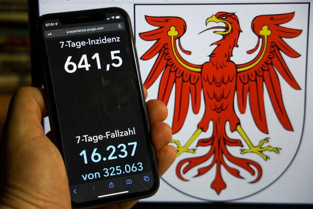 Coronavirus in Germany Covid 19 Dashboard of the Robert Koch Institute DEU, Germany, Brandenburg 12 12 2021 The 7-day incidence for the state Cases last 7 days 100 000 PE is displayed on an iPhone, with the state coat of arms in the background.