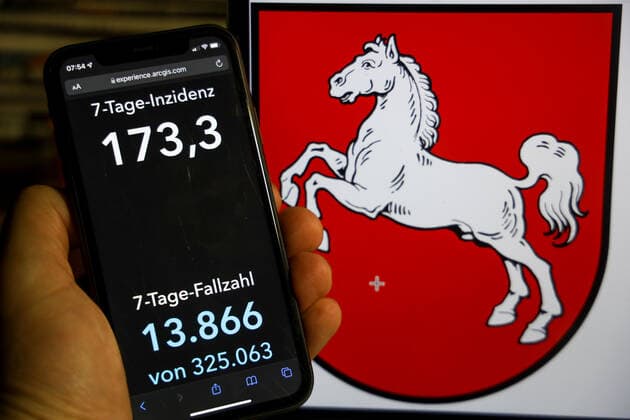 Coronavirus in Germany Covid 19 Dashboard of the Robert Koch Institute DEU, Germany, Lower Saxony 12 12 2021 The 7-day incidence for the state Cases last 7 days 100 000 p.e. is displayed on an iPhone, with the state coat of arms in the background.