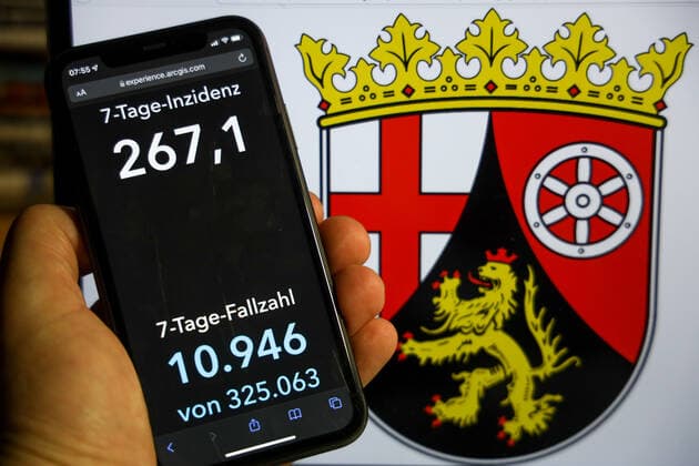 Coronavirus in Germany Covid 19 Dashboard of the Robert Koch Institute DEU, Germany, Rhineland-Palatinate 12 12 2021 The 7-day incidence for the federal state Cases last 7 days 100 000 p.e. is displayed on an iPhone, in the background the state coat of arms