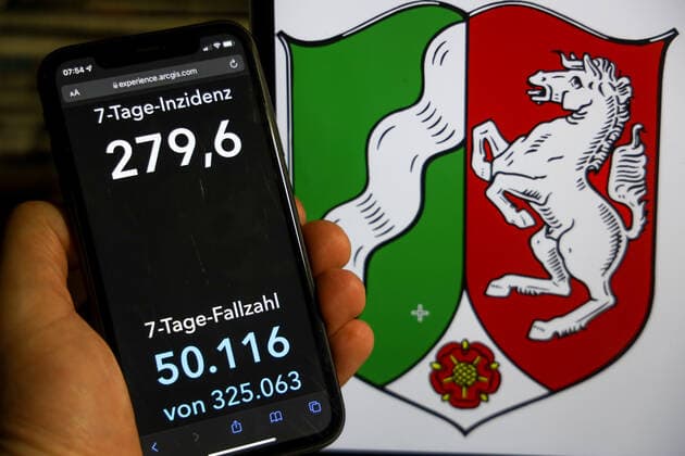 Coronavirus in Germany Covid 19 Dashboard of the Robert Koch Institute DEU, Germany, North Rhine Westphalia 12 12 2021 The 7-day incidence for the state Cases last 7 days 100 000 PE is displayed on an iPhone, with the state coat of arms in the background.