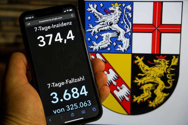 Coronavirus in Germany Covid 19 Dashboard of the Robert Koch Institute DEU, Germany, Saarland 12 12 2021 The 7-day incidence for the state Cases last 7 days 100 000 PE is displayed on an iPhone, with the state coat of arms in the background.