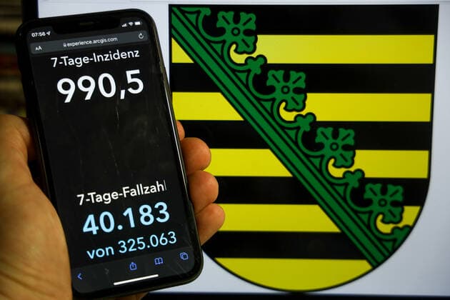 Coronavirus in Germany Covid 19 Dashboard of the Robert Koch Institute DEU, Germany, Saxony 12 12 2021 The 7-day incidence for the state Cases last 7 days 100 000 PE is displayed on an iPhone, with the state coat of arms in the background.