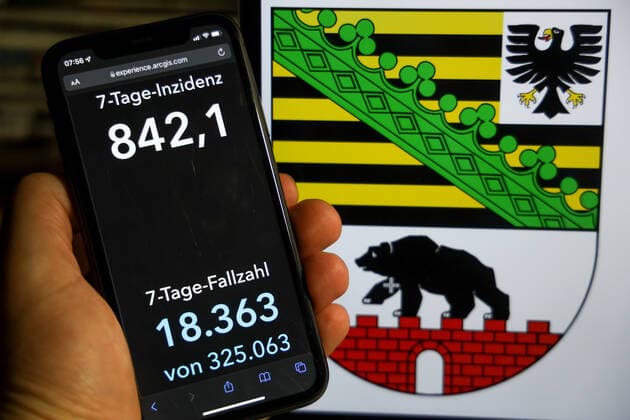 Coronavirus in Germany Covid 19 Dashboard of the Robert Koch Institute DEU, Germany, Saxony Anhalt 12 12 2021 The 7-day incidence for the state Cases last 7 days 100 000 p.e. is displayed on an iPhone, with the state coat of arms in the background.