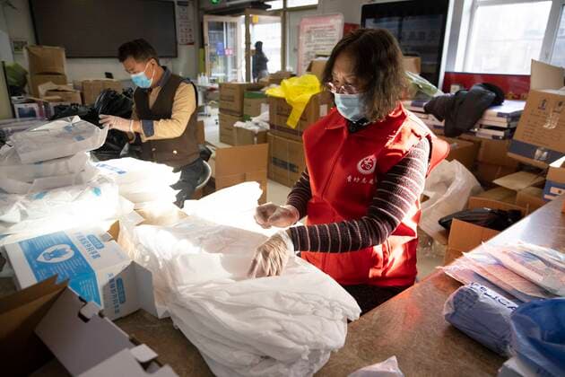 (211212) -- HARBIN, Dec. 12, 2021 -- Wang Tao puts protective gear in place at a subdistrict office in Harbin, capital of northeast China s Heilongjiang Province, Dec. 11, 2021. Clad in protective gear, Guan Chao started his volunteer work with his mother Wang Tao as usual. Guan, 27, is a dance teacher. Due to the latest resurgence of COVID-19 cases in Harbin, his offline teaching routine has been disrupted. Guan joined the fight against the epidemic. He became a volunteer for the citywide nucleic acid testing, medical supplies delivery and regular disinfection on public spaces. Seeing medical staff, community workers and volunteers work day and night, Guan s mother Wang Tao also joined the efforts. Wearing a red volunteer waistcoa 