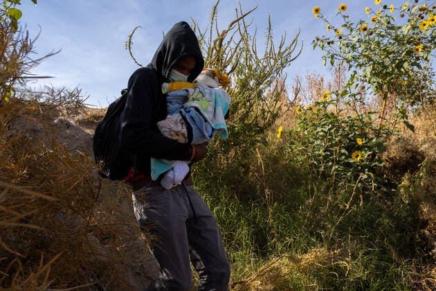 (211214) -- CIUDAD JUAREZ, Dec. 14, 2021 -- A migrant carrying a baby crosses the Rio Bravo river, as seen from Ciudad Juarez, in Chihuahua state, Mexico, on Dec. 13, 2021. (Photo by Xinhua) MEXICO-CIUDAD JUAREZ-MIGRANTS DavidxPeinado 