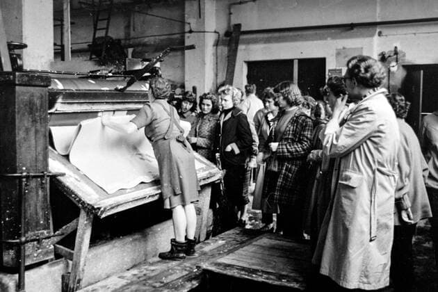Papierproduktion, Papierfabrik Kombinat Heidenau Sachsen Historisches Bild und Foto: Frau zeigt einen Arbeitsgang an einer Maschine im VEB Kombinat Zellstoff, Papier, Pappe und Absatz Heidenau später die Papierfabrik Heidenau GmbH sowie Dresden Papier GmbH in Sachsen, Stadt Heidenau, Landkreis Sächsische Schweiz-Osterzgebirge. 1979 als Rechtsnachfolger der VVB Zellstoff-Papier-Pappe gegründet. Die Aufgaben bestanden in der Entwicklung, Produktion und dem Absatz von Zellstoff, grafischen und technischen Papieren, Verpackungspapieren, Kartons und Pappe. Standorte: VEB HERMES Grafischer Spezialbetrieb Halle Saale, VEB Papierfabrik Greiz, VEB Papierfabrik Hainsberg, VEB Papierfabrik Königstein, VEB Papierfabrik Neu Kaliß, VEB Papierfabrik