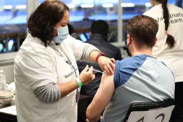 December 18, 2021, London, United Kingdom: A NHS staff from the vaccination team administers a Covid-19 booster jab to a man at a vaccination centre..The Chelsea Stamford Stadium was used as an NHS vaccination centre providing a marathon of jabs ˜Jabathon™. Bookings began from 10am as members of the military and NHS provided the vaccination. London United Kingdom - ZUMAs197 20211218_zaa_s197_132 Copyright: xBelindaxJiaox