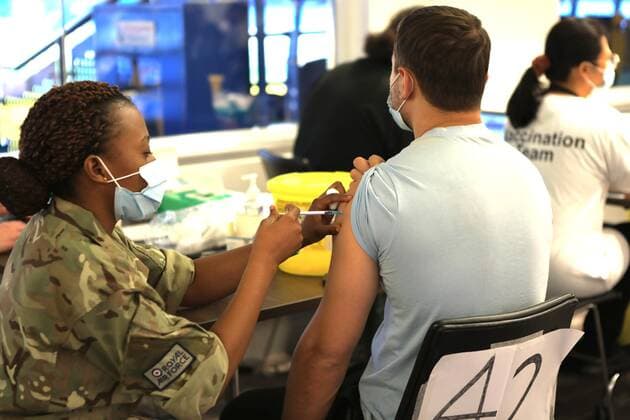 December 18, 2021, London, United Kingdom: A member of the Royal Air Force administers a Covid-19 booster jab to a man at a vaccination centre..The Chelsea Stamford Stadium was used as an NHS vaccination centre providing a marathon of jabs ˜Jabathon™. Bookings began from 10am as members of the military and NHS provided the vaccination. London United Kingdom - ZUMAs197 20211218_zaa_s197_120 Copyright: xBelindaxJiaox