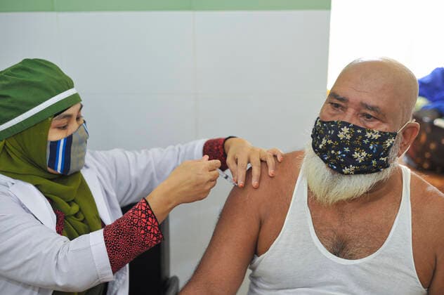 December 20, 2021: 20 December 2021 Sylhet, Bangladesh: A medical staff vaccinating an old age man with the PFIZER Covid-19 Vaccine 2nd dose at the M A G Osmani medical college & hospital vaccination center in Sylhet. Meanwhile, in Dhaka city of Bangladesh launched the COVID-19 booster shot campaign from Sunday with Pfizer vaccine to scale up its efforts for containing the spread of the lethal virus. - ZUMAr143 20211220_zap_r143_017 Copyright: xMdxRafayatxHaquexKhanx