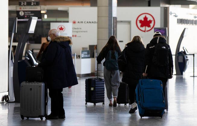 (211221) -- MISSISSAUGA (CANADA), Dec. 21, 2021 -- Travelers wearing face masks are seen at the departures hall of Toronto Pearson International Airport in Mississauga, Ontario, Canada, on Dec. 21, 2021. Canada reported 9,597 new COVID-19 cases Tuesday afternoon, bringing the cumulative total to 1,907,180 cases with 30,082 deaths, according to CTV. (Photo by Xinhua) CANADA-MISSISSAUGA-COVID-19-CASES-1.9 MLN ZouxZheng 