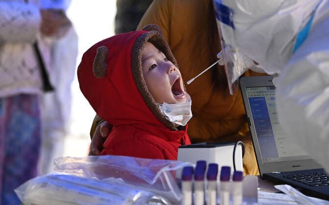 (211225) -- XI AN, Dec. 25, 2021 -- A child receives a nucleic acid test at a testing site in Xi an, northwest China s Shaanxi Province, Dec. 25, 2021. Xi an imposed closed-off management for communities and villages on Thursday in an effort to curb the spread of the latest COVID-19 resurgence. More than 3,000 nucleic acid testing sites in Xi an are working simultaneously to provide services for residents in communities and on roadsides. Tens of thousands of frontline workers and volunteers are working against the clock to contain the virus. To swiftly contain the spread of the virus, local authorities have rolled out urgent measures while ensuring the city s residents have access to daily necessities. ) CHINA-SHAANXI-XI AN-COVID- 