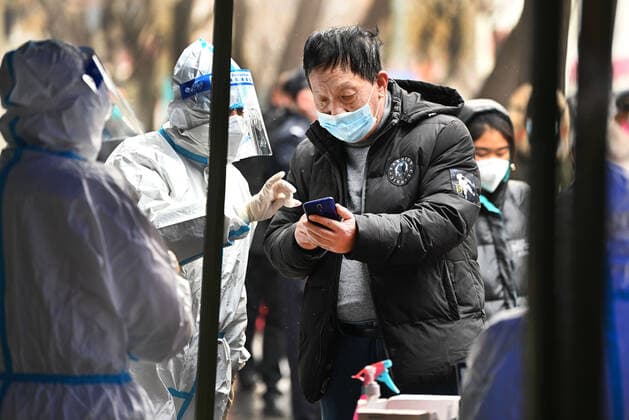 (211225) -- XI AN, Dec. 25, 2021 -- A staff member helps a citizen to scan a QR code at a COVID-19 testing site in Xi an, northwest China s Shaanxi Province, Dec. 25, 2021. Xi an imposed closed-off management for communities and villages on Thursday in an effort to curb the spread of the latest COVID-19 resurgence. More than 3,000 nucleic acid testing sites in Xi an are working simultaneously to provide services for residents in communities and on roadsides. Tens of thousands of frontline workers and volunteers are working against the clock to contain the virus. To swiftly contain the spread of the virus, local authorities have rolled out urgent measures while ensuring the city s residents have access to daily necessities. ) CHINA 