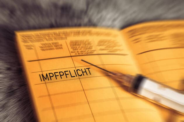 27 December 2021: Impfpflicht - vaccination book with the imprint Compulsory vaccination, symbol image for a General Covid-19 coronavirus Compulsory vaccination, yellow vaccination card