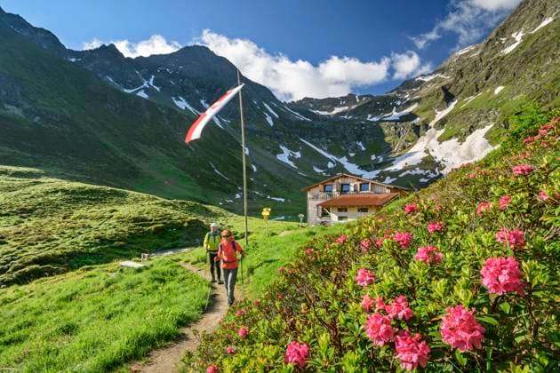 Man and woman hiking in Virgental during spring with Bergerseehutte in background model released, ANSF00090