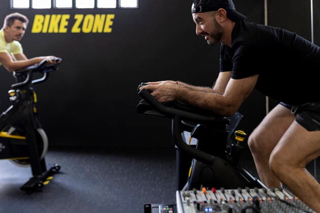 Sportsman looking at friend cycling in gym model released property released, JPTF00946