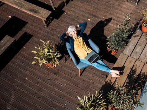 IMAGO Kreativ: Urbane Kultur - Sommer auf den Dächern Businesswoman with hands behind head resting on armchair at rooftop model released property released, JOSEF06043