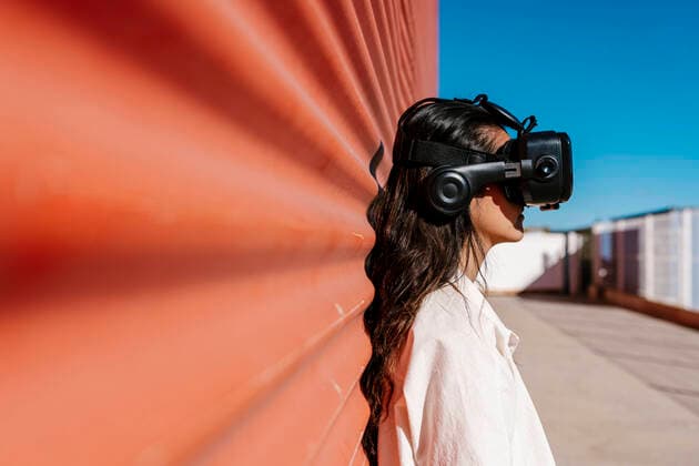 IMAGO Creative: Internationaler Tag der Architektur am 3. Oktober. Thema: Architektur zum Wohlfühlen Woman with virtual reality headset leaning on red wall model released, EGAF02471