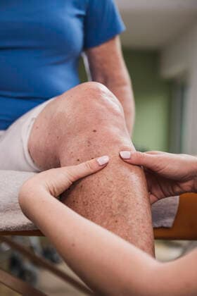 Physical therapist massaging disabled woman s leg at home model released property released, UUF25154