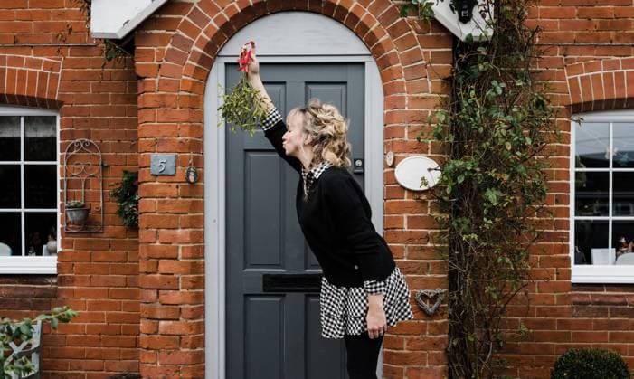 woman holding mistletoe leaning forward for a kiss Winchester, England, United Kingdom CR_RABE220103-885796-01 ,model released, Symbolfoto