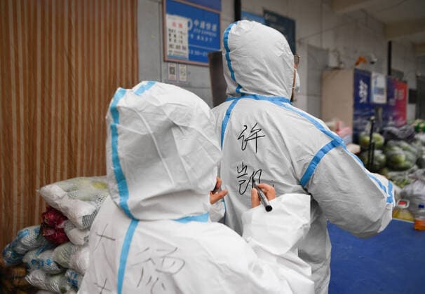 (220105) -- XI AN, Jan. 5, 2022 -- A volunteer writes down Xu Kai s name on his protective suit at Deshan shared kitchen in Yanta District of Xi an, northwest China s Shaanxi Province, Jan. 5, 2022. Located in Yanta District of Xi an, Deshan shared kitchen was run as an anti-cancer kitchen , providing convenience for cancer patients and their families to cook meals. Xu Kai, founder of the shared kitchen, transformed this anti-cancer kitchen into a fight-against-epidemic kitchen after the city has been hit by the recent COVID-19 resurgence. Up to now, more than 30 volunteers have joined the food delivery activities of the kitchen to help not only cancer patients and their families who are stranded in Xi an, but also some personnel wh