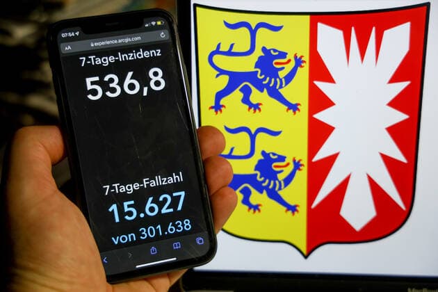 Coronavirus in Germany Covid 19 Dashboard of the Robert Koch Institute DEU, Germany, Schleswig Holstein 09 01 2022 The 7-day incidence for the state Cases last 7 days 100 000 p.e. is displayed on an iPhone, in the background the state coat of arms