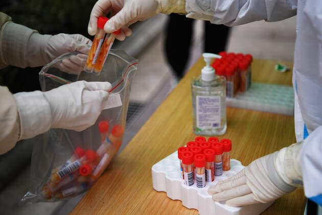 (220110) -- ZHENGZHOU, Jan. 10, 2022 -- A volunteer (L) helps a medical worker collect tubes containing swab sample for COVID-19 tests at a testing site in Zhengzhou, central China s Henan Province, Jan. 10, 2022. The city has carried out rounds of all-inclusive nucleic acid testing to help curb the spread of COVID-19. ) CHINA-HENAN-ZHENGZHOU-COVID-19-TEST (CN) ZhangxHaoran 