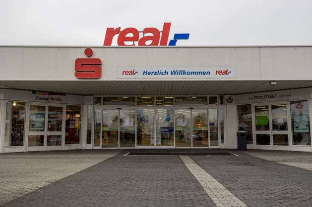 real,- Heidenau Unter dem Logo von der Supermarktkette real,- hängt ein Schild Herzlich Willkommen und und ein S der Sparkasse. Heidenau Sachsen Deutschland *** real, Heidenau Under the logo of the supermarket chain real, hangs a sign Herzlich Willkommen and and an S of the Sparkasse Heidenau Saxony Germany Daniel Schäfer