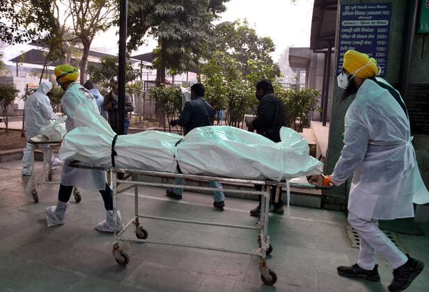 NEW DELHI, INDIA - JANUARY 13: Shaheed Bhagat Singh Sewa Dal volunteers in personal protective equipment (PPE) take out from a hearse the body of a person who died due to the Covid-19 coronavirus, at a cremation ground at crematorium Center Old Seema Puri Ghat, on January 13, 2022 in New Delhi, India. (Photo by Sonu Mehta Hindustan Times ) Daily Life Amid Coronavirus Pandemic In India