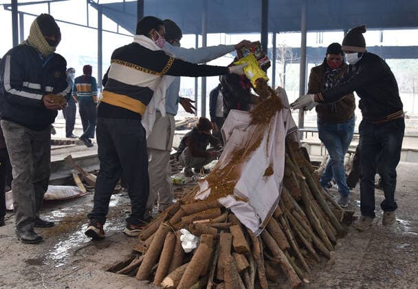 NEW DELHI, INDIA - JANUARY 13: Relatives of a Covid-19 victim performs the last rites attend the funeral of a person who died from coronavirus disease (COVID-19), at crematorium center Old Seema Puri Ghat, on January 13, 2022 in New Delhi, India. (Photo by Sonu Mehta Hindustan Times ) Daily Life Amid Coronavirus Pandemic In India