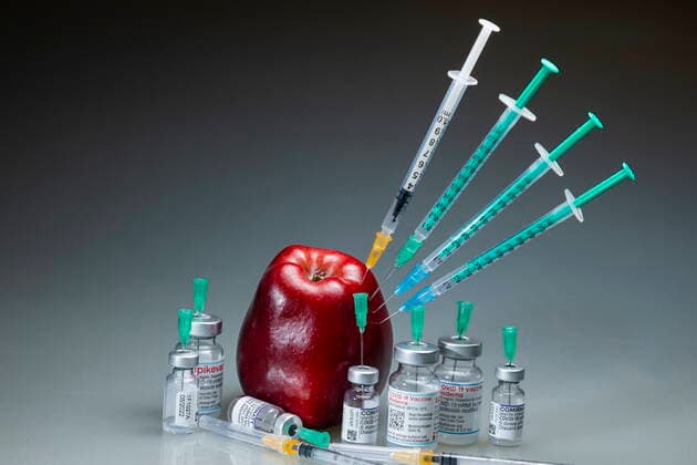 Covid motif symbol image vaccination a corona syringe is stuck in a red apple Bannewitz Saxony GERMANY