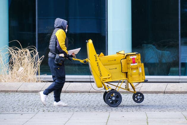Düsseldorf 20.01.2022 Post DHL Brief Briefe Briefzustellung Zusteller Briefpost Posthorn Postbote Postzusteller Briefzusteller Trolley Düsseldorf Nordrhein-Westfalen Deutschland