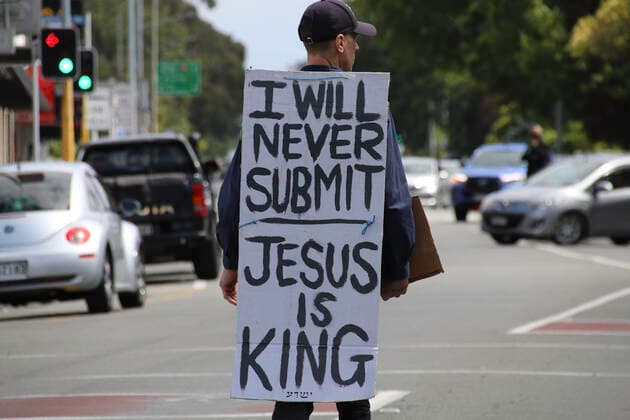 January 22, 2022, Christchurch, Canterbury, New Zealand: A protester is seen in the middle of Papanui rd ahead of the antivax protest with a placard that reads I will never submit, Jesus is King ..Protesters take to the streets in the affluent suburb of Merivale in protest against the mandatory Covid19 vaccination. Christchurch New Zealand - ZUMAs197 20220122_zaa_s197_025 Copyright: xAdamxBradleyx