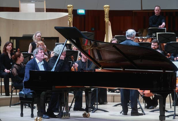 MOSCOW, RUSSIA â€” JANUARY 22, 2022: Pianist Boris Berezovsky (L front seated) and conductor Valery Gergiev (R midground standing) perform with the Mariinsky Theatre Symphony Orchestra at Zaryadye Concert Hall. The concert was organised by Valery Gergiev Foundation. Sergei Fadeichev TASS  TS11FFDF