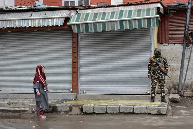 January 22, 2022, Srinagar, Jammu & Kas, India: A woman walks past a paramilitary trooper standing guard at a closed market during a lockdown imposed by the authorities following the surge in coronavirus cases in Srinagar..Kashmir has been witnessing an exponential surge in Covid-19 cases following which authorities imposed a 64-hour lockdown to curb the surge. Jammu and Kashmir on Friday reported 5,720 coronavirus cases and five deaths. Meanwhile, India reported 337,704 new Covid-19 cases in the last 24 hours. Srinagar India - ZUMAs197 20220122_zaa_s197_073 Copyright: xSaqibxMajeedx