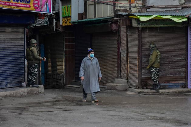 January 22, 2022, Srinagar, Jammu & Kas, India: A man wearing a face mask walks past paramilitary troopers standing guard at a closed market during a lockdown imposed by the authorities following the surge in coronavirus cases in Srinagar..Kashmir has been witnessing an exponential surge in Covid-19 cases following which authorities imposed a 64-hour lockdown to curb the surge. Jammu and Kashmir on Friday reported 5,720 coronavirus cases and five deaths. Meanwhile, India reported 337,704 new Covid-19 cases in the last 24 hours. Srinagar India - ZUMAs197 20220122_zaa_s197_076 Copyright: xSaqibxMajeedx