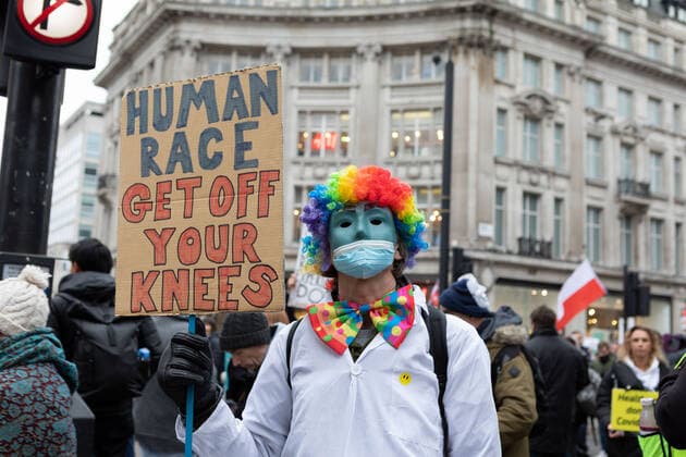 January 22, 2022, London, England, United Kingdom: A protestor seen dressed in medical uniform and as a clown holding a placard that says human race get off you knees during the demonstration..By April 2022, 100k members of the NHS will have to be fully vaccinated or lose their jobs. In light of this draconian requirement, NHS nurses have come together to protest against such coercion, defending their medical freedom and accusing the government for a total mistreatment of the health workers over the pandemic. Other anti-lockdown and anti-vaccine groups have jointly protested against the restrictions imposed by the government, and threaten to take to the streets should the restrictions not be lifted by 27th Jan 2022. London United Kingdom - ZUMAs197 20220122_zaa_s197_158 Copyright: xBelindaxJlaox