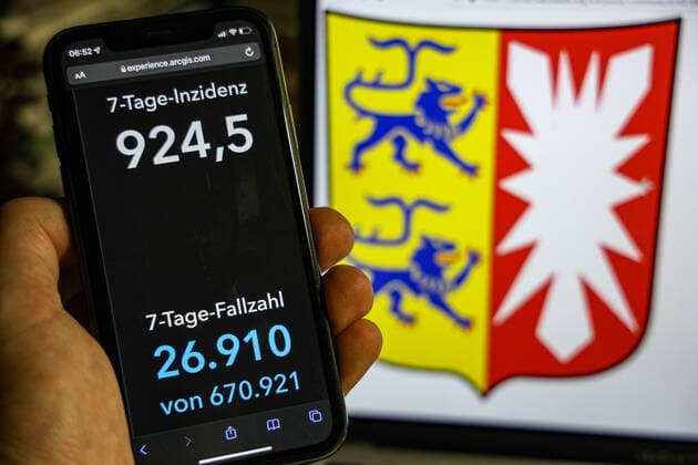 Coronavirus in Germany Covid 19 Dashboard of the Robert Koch Institute DEU, Germany, Schleswig Holstein 23 01 2022 The 7-day incidence for the state Cases last 7 days 100 000 p.e. is displayed on an iPhone, in the background the state coat of arms