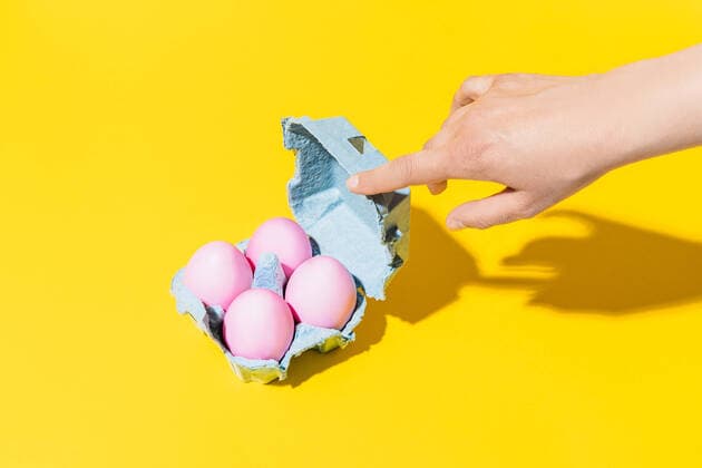 IMAGO Creative: Ostern Hand of an unknown woman opening an egg cup with pink eggs on a yellow background AlvaroSanchez_EasterStillLife_3.jpg Copyright: xAlvaroxSanchezx Model Released