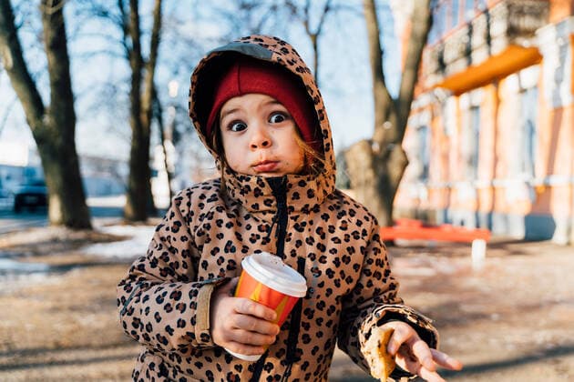 IMAGO Creative: Winter in der Stadt Cute amazed girl in warm clothes with takeaway drink and cookie looking at camera while standing on street in winter day, Model released OleksandraTroian_KidOutdoorsInWinter_20.jpg Copyright: xOleksandraxTroianx MR