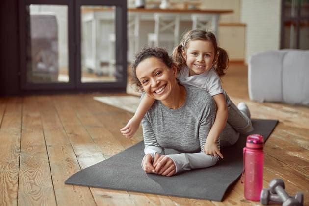IMAGO Creative: Internationaler Frauentag, Mental Load und Care-Arbeit Happy mom and daughter spending active time indoors Waist up portrait of smiling woman and girl lying on mat at home while doing training Copyright: xx 40740642