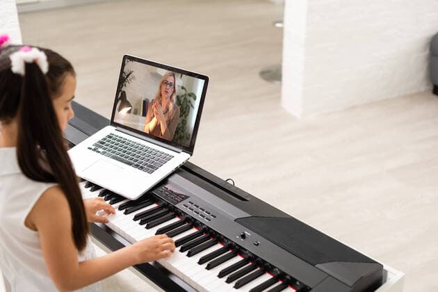 IMAGO Creative: Bildung, Musikerziehung little girl play piano in class education with laptop in home online learning in covid-19 crisis quarantine little girl play piano in class education with laptop in home online learning in covid-19 crisis quarantine. Copyright: xsinenkiyx 43159528